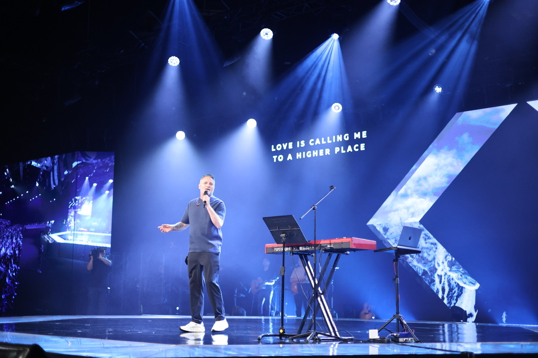 Mark Stevens leading worship on stage beside a keyboard