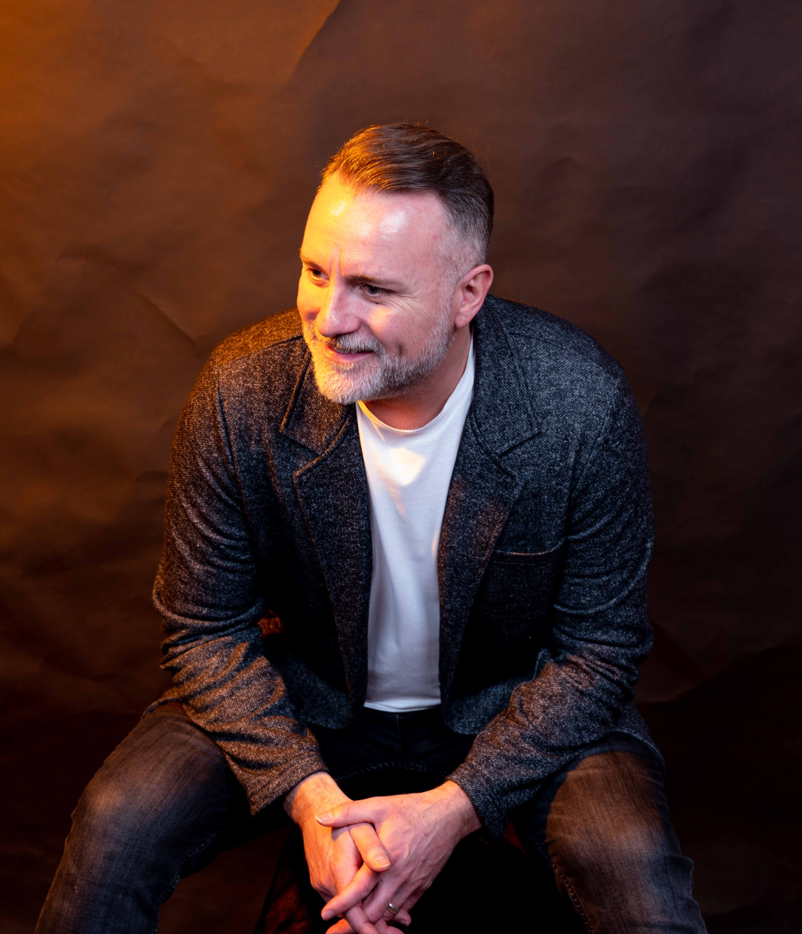 Mark Stevens seated in a grey jacket with warm golden lighting