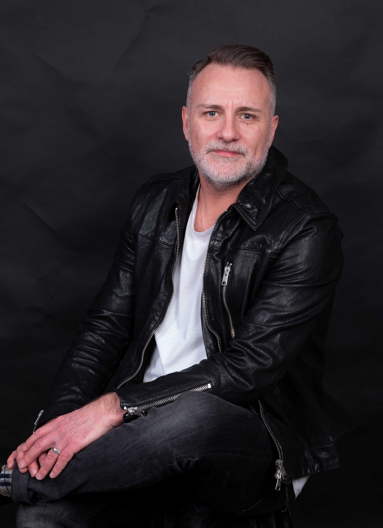 Mark Stevens seated in a black leather jacket